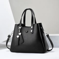Minimalist black leather tote bag with silver hardware and heart charm on white background - Black