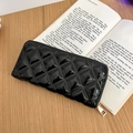 Detailed macro of black quilted patent leather wallet with elegant gold zipper and sewing - Black