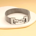 Primer plano de pulsera de malla plateada con cierre geométrico sobre piedra - Pulsera de Malla Milanesa con Hebilla Geométrica de Moda (CK1148) / Color Acero
