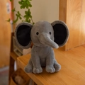 Cute grey plush elephant toy with soft fabric and black ear details in a sitting pose - Gray