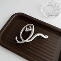 Sleek silver metal claw clip with streamlined spiral design on a wooden tray - Large Silver Q-Shape