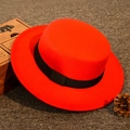 Roter flacher Wollfilzhut mit schwarzem Band auf einem strukturierten Teppichboden - Erwachsenengröße 55-58cm / Rot