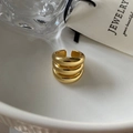 Makro-Detail von hochglanzpoliertem, vergoldetem dreischichtigem Ring auf Keramik - Dreischichtige Offene Ring / Gold