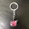 Close-up of a glass keychain with dried pink flowers and a silver alloy chain link - Rose Red Lace Flower
