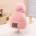 Close-up of pink knitted kids hat with a fluffy pompom and stitched OK patch detail - One Size (2-5 Years) / Pink