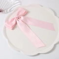 Barrette à cheveux avec nœud en satin rose sur une assiette décorative blanche - Rose