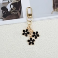 Golden keychain featuring three black enamel flower charms and secure lobster clasp - Black