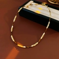 Vista de cerca del collar de cuentas marrones y blancas con detalles dorados - café