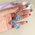 Handheld detail of blue translucent resin dice keychain with metal ring and chain link - Light Blue