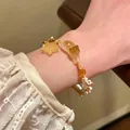 Pulsera tejida a mano en hilo dorado con dije de gato amarillo translúcido y estrella - Pulsera de Cuerda Tejida con Gato y Estrella