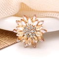 Elegant champagne sunflower brooch featuring marquise crystals on a vintage newspaper background - Champagne