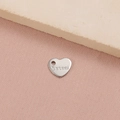 Vista macro de un pequeño colgante de corazón de acero inoxidable con grabado - Etiqueta Corazón S.Steel (8#) / Color Acero