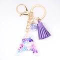 Detailed view of resin letter A keychain with colorful stones, purple tassel and gold hardware - Letter A