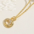 Close-up of interlocking circular gold pendants with zircon paving on textured background - Interlocking Rings (14K Gold Plated) / Gold