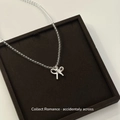 Minimalist beaded necklace with silver bow pendant displayed on a velvet jewelry tray - White Glass Bead Bowknot Pendant Necklace