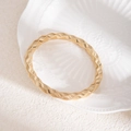 Détail d'un bracelet spirale doré au design tressé sur une assiette décorative - Bracelet à texture tissée dorée (L715)