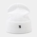Close-up of white knitted beanie featuring black N letter embroidery and thick texture - White