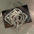 Macro shot of white pearl necklace with metal clasp inside a clear protective plastic bag - Thin Style / Large Square