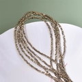Close-up of 2mm bronze square hematite beads on red strings over a ceramic tray - Antique Gold