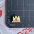 Vue détaillée d'une mini breloque château de sable en résine avec règle de mesure - Château de Sable