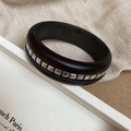 Détail macro d'un bracelet en bois foncé avec clous carrés argentés sur boîte blanche - Noir Avec Rivets Carrés