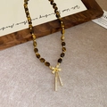 Detailed macro view of tiger eye stone necklace with gold bow pendant on wood frame - Gold Bow Tiger Eye Tassel (22#)