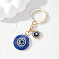 Makro-Detail des goldenen Evil Eye Schlüsselanhängers mit blauem Emaille und Strasssteinen - Gold Rund Blaues Auge