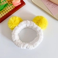 Plush white headband with two yellow pom-poms displayed on a wooden decorative tray - Yellow