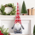 Close-up of a Christmas gnome doll with a red knit hat and grey overalls on a fireplace - Red Hat Gnome Doll