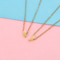 Detailed view of two split heart gold-tone necklaces on a pastel pink and blue background - Gold