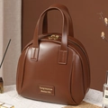 Braune Make-up-Tasche aus Kunstleder mit Tragegriff auf weißem strukturiertem Stoff - Große Muscheltasche Kaffee