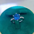 Macro detail of a 2-carat blue gemstone ring with six-prong setting on green velvet - A6 Open Type / Blue