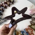 Detailed view of hollow star hair claw clips in various colors and metallic spring - 11cm / Chocolate