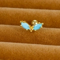 Vue macro de piercing d'oreille papillon doré avec pierre bleue sur plateau velours - Papillon / Or / Bleu Ciel