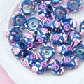 Macro shot of blue hand-painted glass beads with pink spirals on a white ceramic plate - Transparent Bead Royal Blue Cream Rose Red Circle