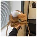 Detailaufnahme einer kamelbraunen Handtasche mit Krokoprägung und weißem Bommel - Khaki