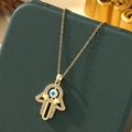 Detail of Hamsa Hand necklace with Evil Eye and white zircons on a green gift box - A10-Gold