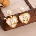 Dettaglio degli orecchini a cuore in perla con rosa dorata su una scatola di legno scuro - Stile Bianco (2-26367A-7800)