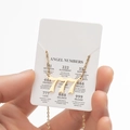 Golden stainless steel angel number 777 necklace on a white symbolic meaning card - 777 / Gold