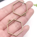 Pair of bronze hexagonal hollow alloy pendants for DIY jewelry held in hand - Hexagon Bezel (22237) / 29x28mm / Bronze