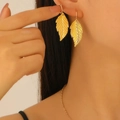 Elegant gold leaf dangle earrings with realistic texture worn by a female model - Leaf Shaped Earrings (10723) / Gold