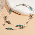 Detail einer Vintage Doppelhalskette mit türkisen Ovalperlen und floralen Metallelementen - Blau Rund