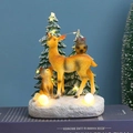 Close-up of lighted resin Christmas ornaments featuring deer and owl on books - Deer