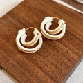 Vista dettagliata degli orecchini a doppio cerchio placcati oro 18k su supporto in legno - Bianco (Placcato Oro 18K)