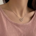 Elegant silver heart pendant necklace shown worn on a model with a soft pink background - Twisted Heart Necklace