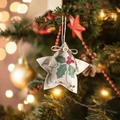 Star-shaped linen Christmas ornament with holly berry print hanging on a tree - Pentagram