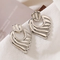 Pendientes minimalistas de metal plateado con forma de onda sobre fondo de tela blanca - Forma de corazón/ala / Plateado