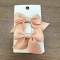 Two-piece set of light pink bow hair clips on white card over dark wood background - Flesh Pink