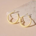 Detailed close-up of cream yellow geometric hoop earrings on a beige textured stone base - Silver Needle Small Hoop / Yellow