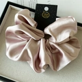 Detail of a large champagne satin scrunchie with a handmade tag on a textured tray - 18cm / Pearl Pink